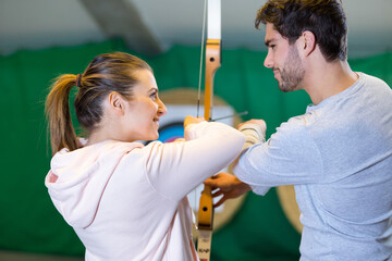 man and woman are shooting with bows practicing archery