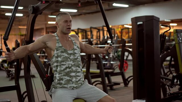 Muscular athletic bodybuilder sitting bench training chest muscles on fitness equipment pec deck fly working out strength Sport fitness healthy lifestyle Man do flyes exercises on gym machine