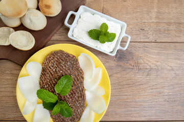 raw quibe with sliced onion, dried curd, pita bread and mint leaves