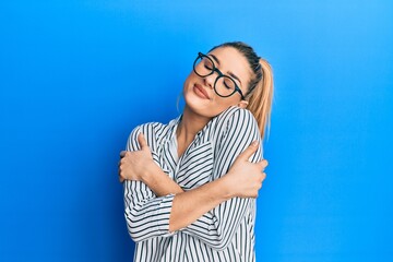 Obraz na płótnie Canvas Young caucasian woman wearing business shirt and glasses hugging oneself happy and positive, smiling confident. self love and self care