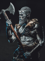 Northern warrior risen from the dead with pale skin and two handed axe in armour with fur in dark...
