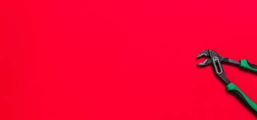 A quality green sliding pliers building tools to repair a car or house on red background with copy space. Do it yourself instruments. Banner for advertising construction shop. Business card