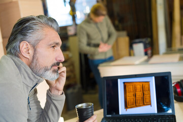 mature man in workshop by laptop showing wardrobe