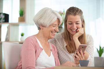 mother with daughter sitting on sofa using social media