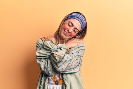 Young beautiful woman wearing hippi clothes hugging oneself happy and positive, smiling confident. self love and self care