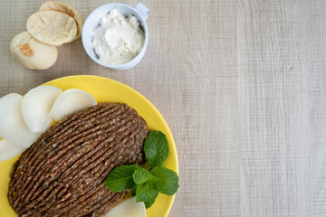 raw quibe with sliced onion, dried curd, pita bread and mint leaves
