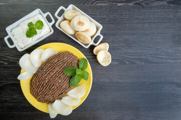 raw quibe with sliced onion, dried curd, pita bread and mint leaves