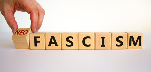 Neofascism symbol. Man hand turns a cube and changes the word fascism to neofascism. Business and fascism or neofascism concept. Beautiful white background, copy space. - obrazy, fototapety, plakaty