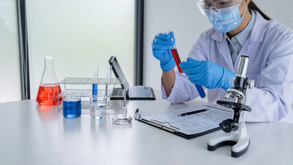Fototapeta premium Medical or scientific researcher or man doctor looking at a test tube of clear solution in a laboratory