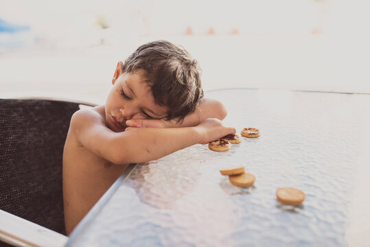 Authentic image of a small child who falls asleep while eating chocolate cookies, with a dirty face.