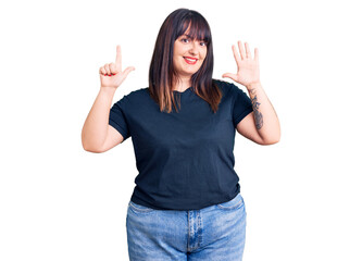 Young plus size woman wearing casual clothes showing and pointing up with fingers number seven while smiling confident and happy.