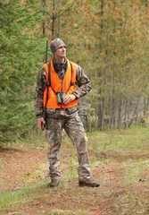 Fotobehang modern deer hunter standing in forest full length © Nathan Allred