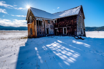 Abandon homestead on a high prairie with a sunburst