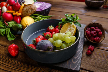 Fototapeta na wymiar Fruits and berries in plate on wooden background