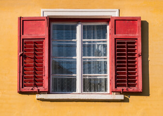 Detail of a window with old wooden shutters on a orange wall in medieval town of Sighisoara, Romania.