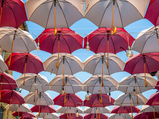 Suspended colored umbrellas and light bulbs against blue sky.
