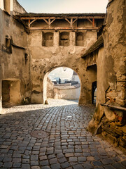 Cobblestone street between the walls of Sighisoara fortress in Romania.