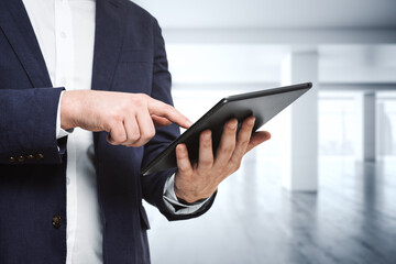 Man using digital tablet in bright sunny office, close up. Technology concept