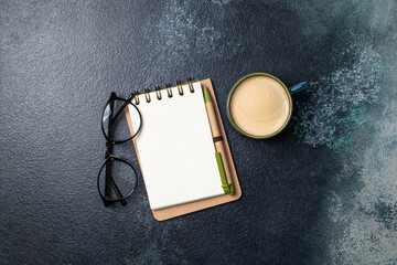 White blank notebook and coffee cup on office table. Flat lay desk with business accessories open notepad and cup of coffee. Copy space, top view
