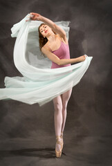 Fototapeta na wymiar Young woman dancing with green fabric flying in the studio.
