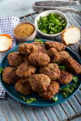 Minced meatball in dish with spices and parsley on wooden background. 