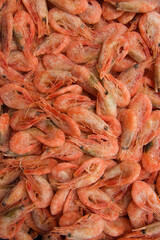 Close-up of a heap of frozen orange shrimp. Peel the shrimp, leaving only the tails. Seafood background. Top view, vertical format.