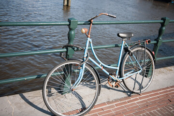 Fototapeta na wymiar Rusty old bike locked to bridge in Amsterdam stock picture