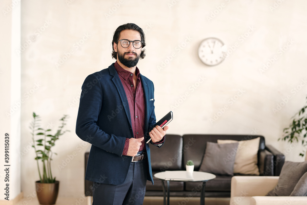 Poster happy young elegant businessman with notebook standing in front of camera
