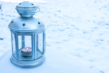 Lantern with burning candle covered with snow. Winter mood and Christmas holidays concept. Copy space