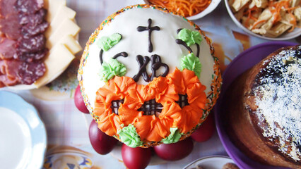 Decorating with flowers from bright glaze on a traditional Easter kulich. Authentic Christian Orthodox treat for Easter. Religious dishes. View from above. Selective focus.