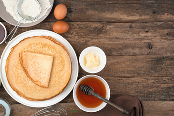 Cooking background with pancakes and ingredients for cooking them on a brown background. Top view, with space to copy. The concept of cooking, Mardi Gras.