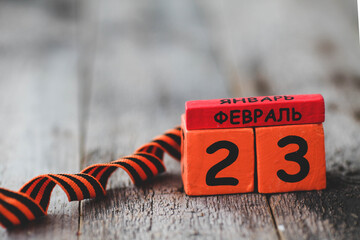 Wooden calendar with the date February 23 and george ribbon . Fatherland defender day. Father day....