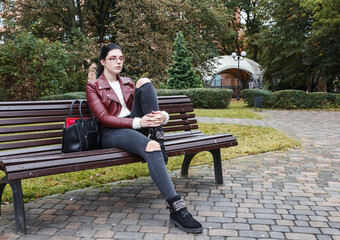 young girl sitting on a park bench in autumn