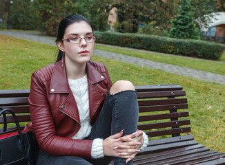 young girl sitting on a park bench in autumn