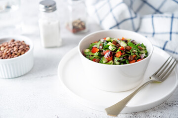 Green lentil red bell pepper cucumber parsley salad in a bowl