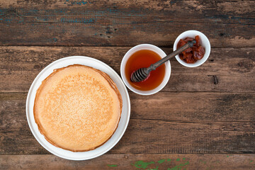 Maslenitsa, pancakes with honey and jam on a brown wooden background. Top view, with space to copy. Concept of culinary backgrounds.