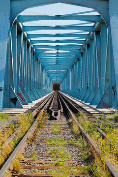 Blue steel railroad bridge with dual gauges at the national border between Sweden and Finland.