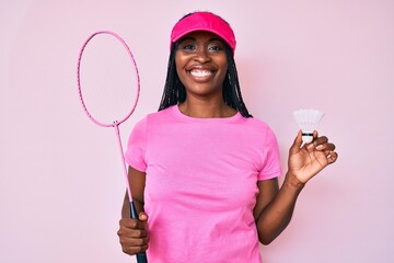 African american woman with braids holding badminton racket smiling with a happy and cool smile on face. showing teeth.