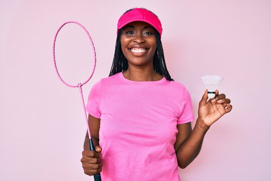 African american woman with braids holding badminton racket smiling with a happy and cool smile on face. showing teeth.
