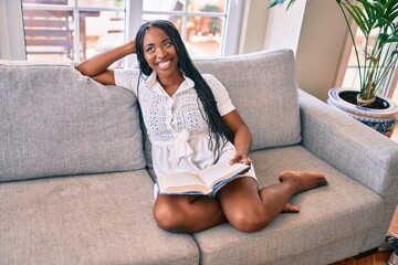 Obraz premium Young african american woman smiling happy reading book at home