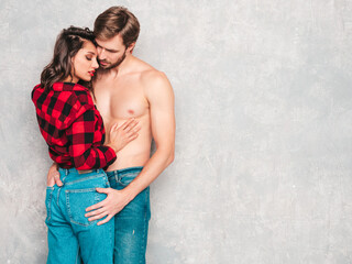 Hot beautiful woman and her boyfriend. Models posing near gray wall in jeans clothes. Young passionate couple hugging before having sex. Sensual pair getting closer.He touching her ass hard with hands