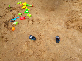 Concept of beach recreation for children. Bright plastic children's toys in the sand. Top view. Space for text