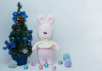 Knitted plush bunny near the Christmas tree