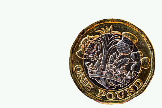 Close up of a one pound coin standing on its edge against a plain white background.. No people. Copy space.