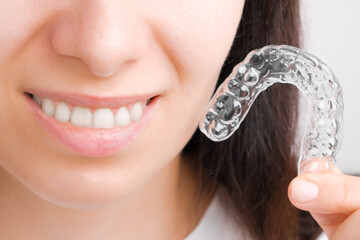 Close up woman holding a transparent removable braces for perfect smile. Orthodontic aligners for...
