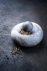 Modern design minimalistic mortar with black pepper berries as close-up on a rustic board with copy space