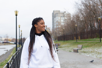 happy African American woman in a Park in a white hoodie