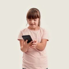 Portrait of disabled girl with Down syndrome holding smartphone, looking at the screen while posing isolated over white background