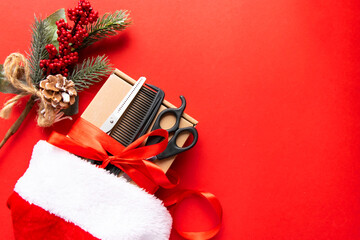 Flat lay Christmas composition. Hairdressing tools, gift and Christmas decor in a Santa Claus hat on a red background. Xmas, happy new year