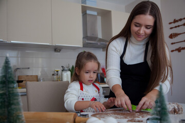 Fototapeta premium Caucasian mother and daughter cooking ginger bread in the kitchen. Christmas cooking concept. Mother and daughter cooking concept. 